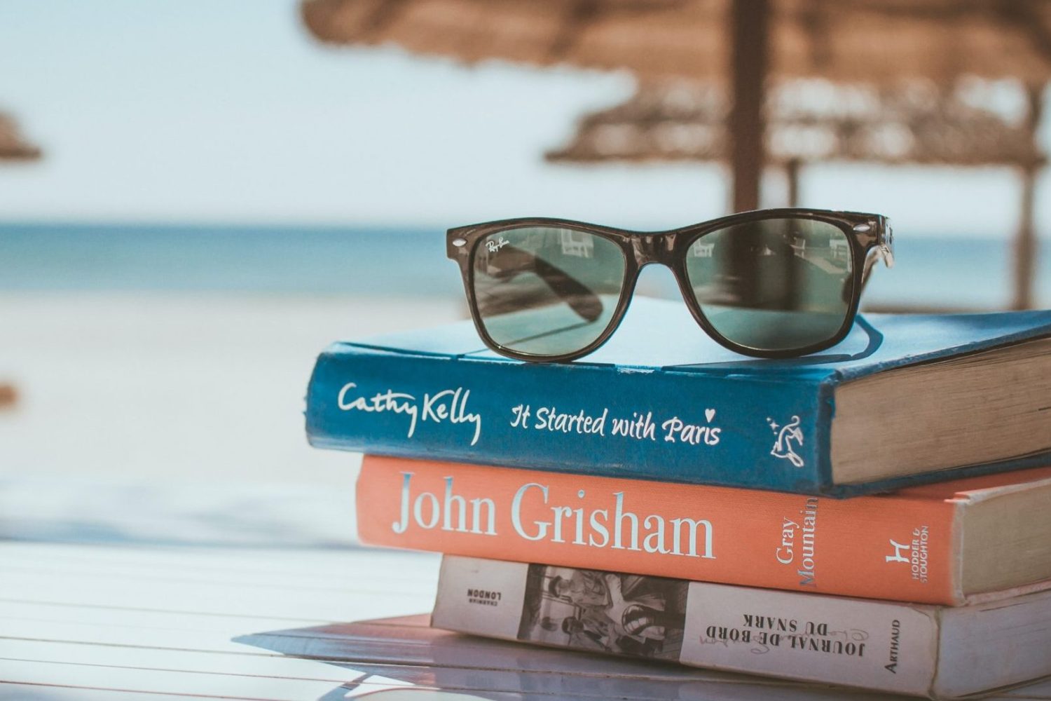 Stack of teacher's books and sunglasses in summer on the beach