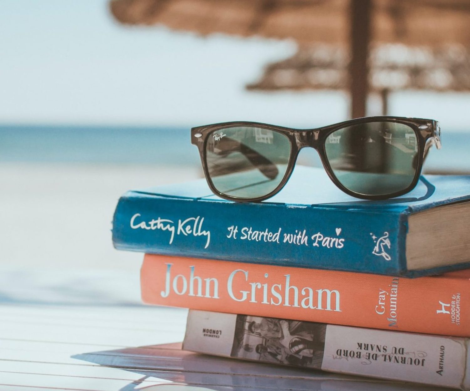Stack of teacher's books and sunglasses in summer on the beach